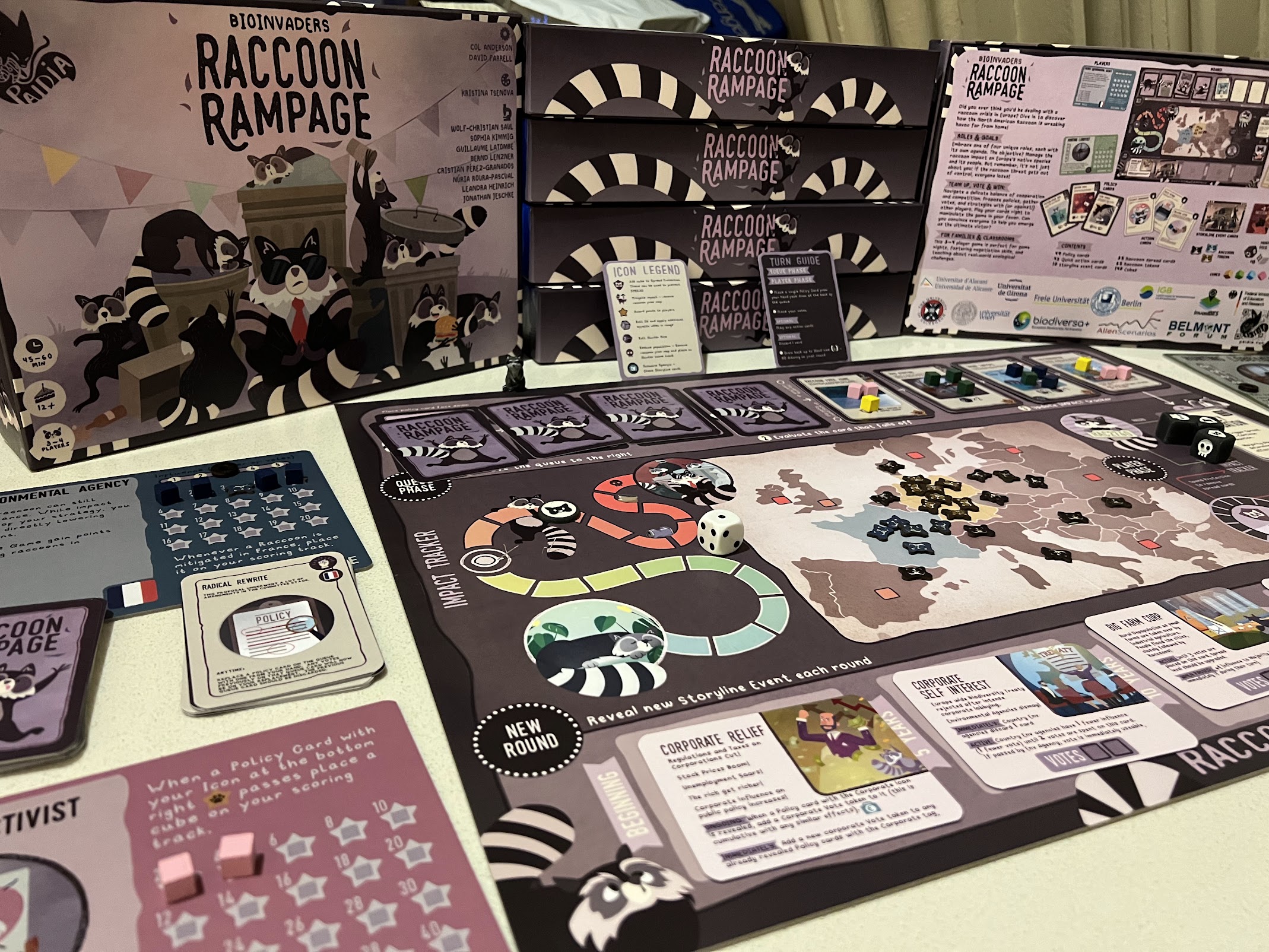 Raccoon Rampage boardgame set up on a table, components include an eye catching board, dice, raccoon tokens, player mats and cards